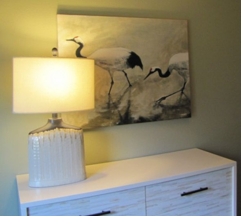 Lovely grouping of art and a lamp with a dresser.