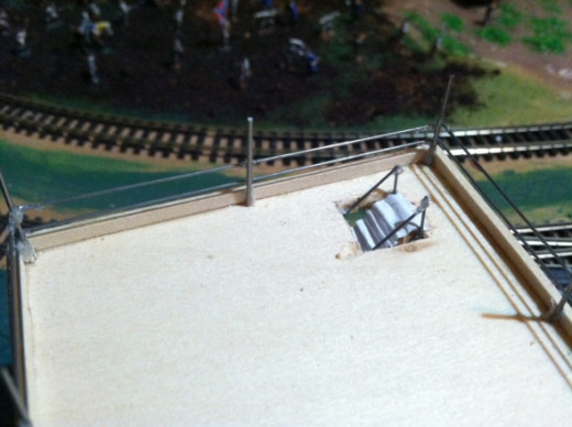 The steps emerging through the platform. To give the edge of the hole a more finished look, attach tiny basswood strips around three sides. Leave the side open where miniature people will enter or exit