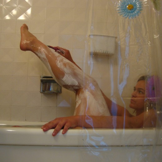 A woman shaving her legs with a disposable razor.