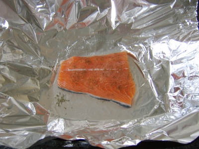 The salmon fillet is seasoned and drizzled with white wine