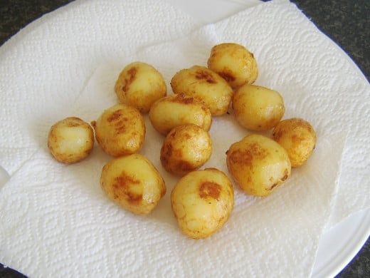 Pan roasted potatoes are drained on kitchen paper