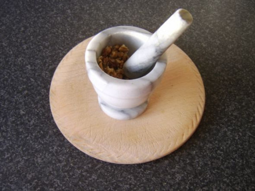 Walnuts are crushed with a pestle and mortar