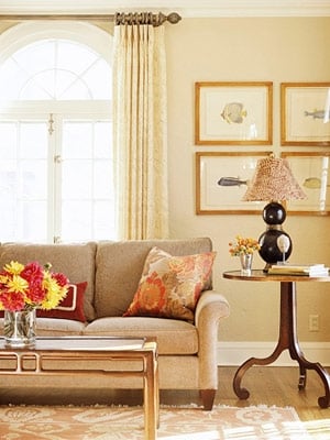A living room is cozy for family time but retains an air of style for entertaining. Accessories such as a gourd lamp with a feather-covered shade bring panache to the space. To add a subtle beach element, antique hand-painted fish prints hang behind 