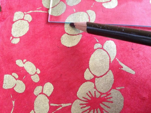 Step 6. Carefully lift the frame from the paper, leaving only the glass, and sketch a light line around the glass. Then, using the T-square and your paper-cutting shears or an Exacto knife, cut the paper along the sketch lines. 