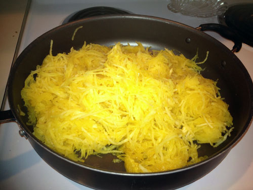 Place shredded squash in a large skillet pan over medium heat. Place pats of margarine on top of the squash and cover. Cook until margarine melts.