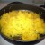 Place shredded squash in a large skillet pan over medium heat. Place pats of margarine on top of the squash and cover. Cook until margarine melts.