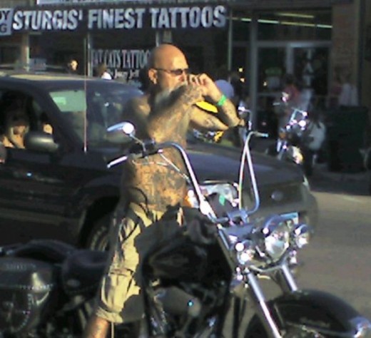 A biker stops riding in middle of street to take a cell phone call - in Sturgis.
