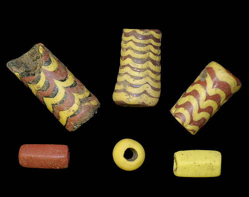 Cylindrical beads. The red and yellow ones, bottom right and bottom left, are pentagonal. The beads were found in Saxon graves at Cliffs End.