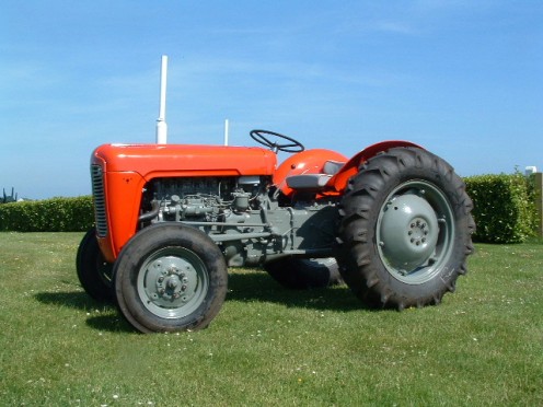The red tractor parked next to the barn.
