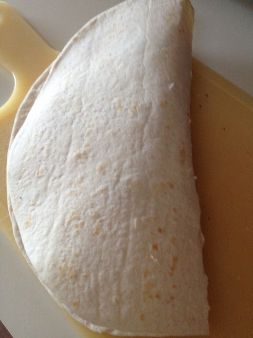 Fold the tortilla in half.  Then place in a preheated pan or griddle coated with oil.