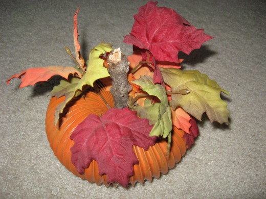 My mother made this with orange spray paint, a thick twig and faux leaves.