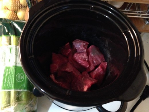 Stew meat at the bottom of the crock pot.