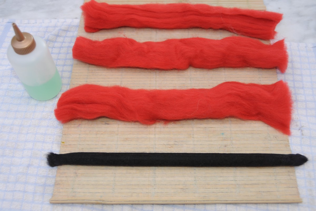 Two black layers felted and lying alongside three layers of red wool roving