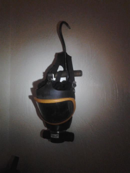 Gas mask hanging from a meat hook