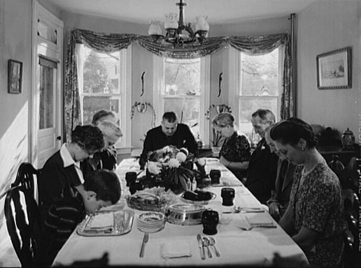 A classic picture of a family gathered around the table to pray and thank God for their blessings and food.