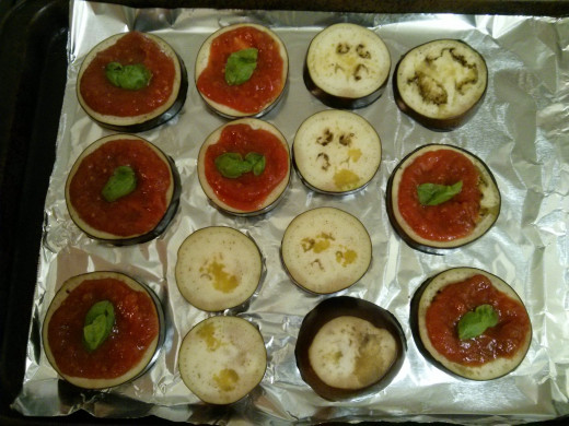 First layer of eggplant - covering the larger pieces of eggplant with tomato sauce and a basil leaf