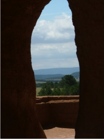 The remains of an arched doorway frames the plateau on which the mission stands in the Sangre de Cristo Mountains near Santa Fe, New Mexico.