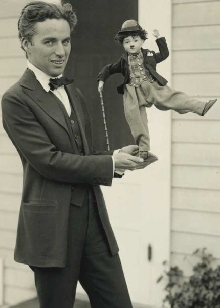 An antique Charlie Chaplin celebrity doll being held by the man himself.