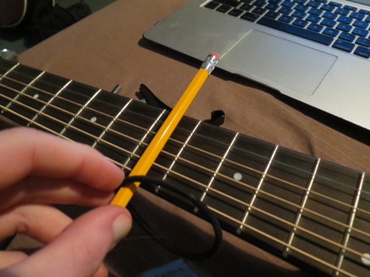 Start with the rubber band (in this case an elastic hair band) at the top of the pencil.