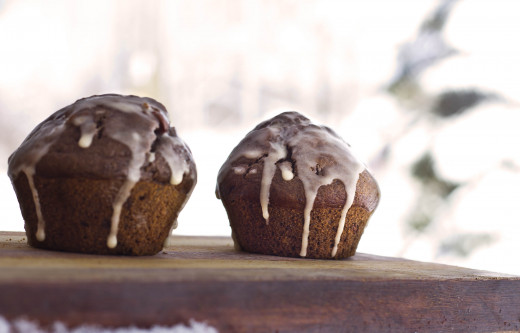 Freshly baked chocolate chocolate chip muffins, complete with orange glaze, with a super snowy backdrop.
