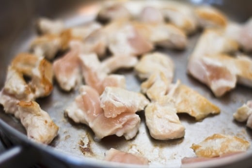 Strips of chicken cooking in a frying pan.