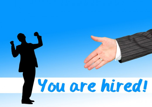 You Are Hired colorful sign with handshake and silhouette cheering