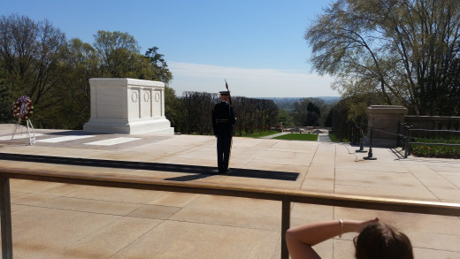 The soldier stands at attention, and waits to walk back across the mat. 