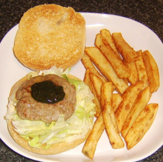 Lamb burger on a lettuce bed on a bread roll with mint sauce and served with homemade chips