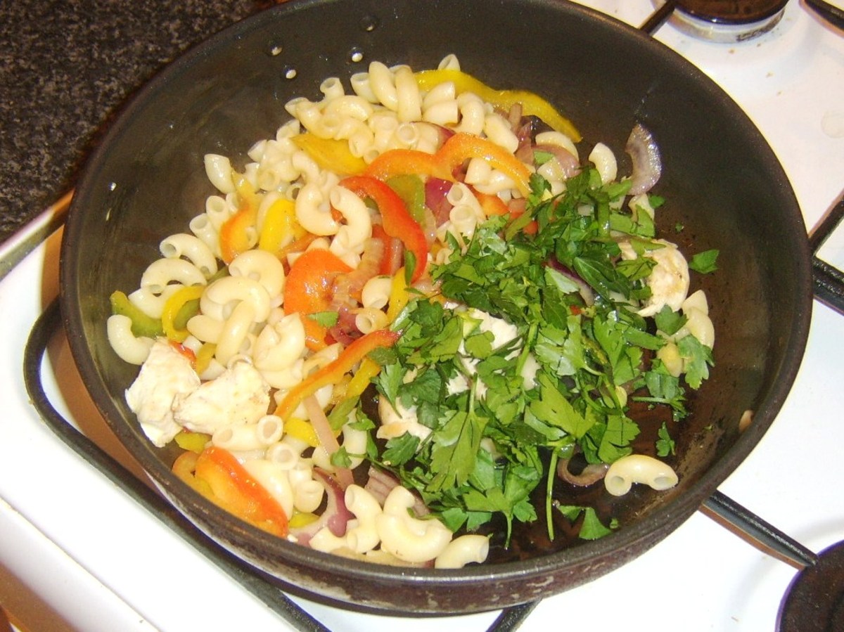 Freshly chopped parsley is added to macaroni and chicken stir fry