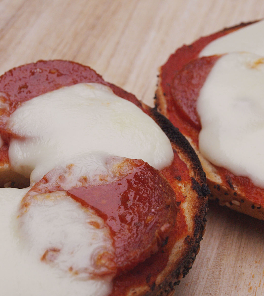 A pizza bagel with sauce, mozzarella cheese, and pepperoni sausage.