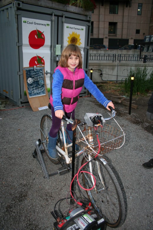 My daughter on a bicycle set up to use pedaling as an energy source at Occupy Boston.