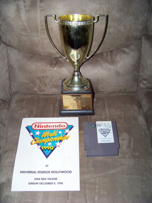 The trophy that was awarded to the 1990 Nintendo World champion, and the gray cartridge that was used to compete in the tournament. 