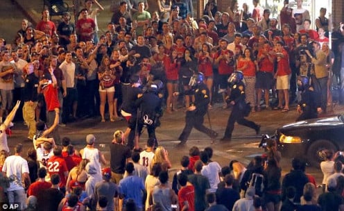 Tucson Police Officers rush out of their line to take a man into custody who had been taunting them and riling up a crowd of fans in Maingate Square following Arizona's loss to Wisconsin 64-63 in the West Region NCAA final.