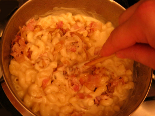 Stirring the bacon, onion and cheese sauce into the macaroni.