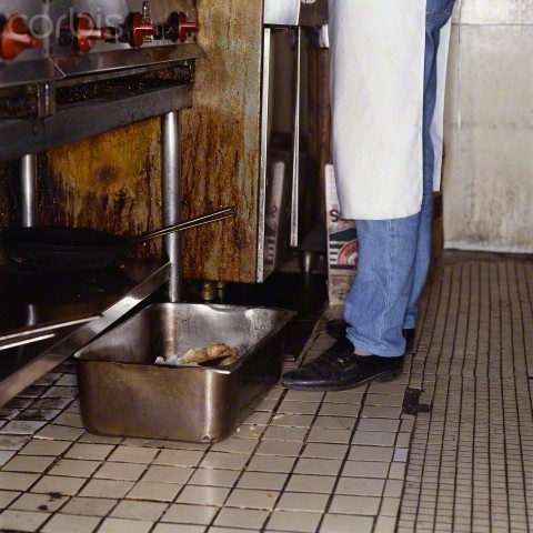 A dirty restaurant's kitchen area always has water sitting in pans, cans, and in the floor.