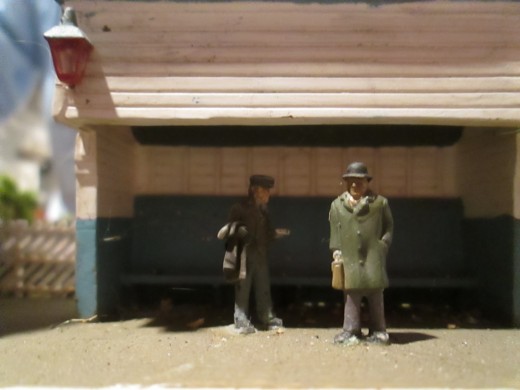 A couple of passengers in the open-fronted shelter, waiting (picture was taken facing backwards, as the shelter front looks away towards the goods depot opposite)