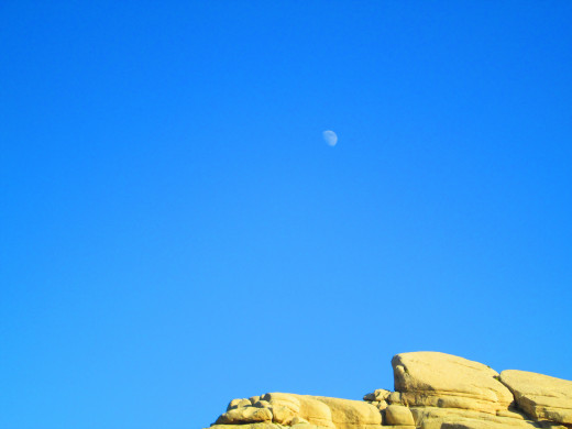 The moon above the boulder formation.