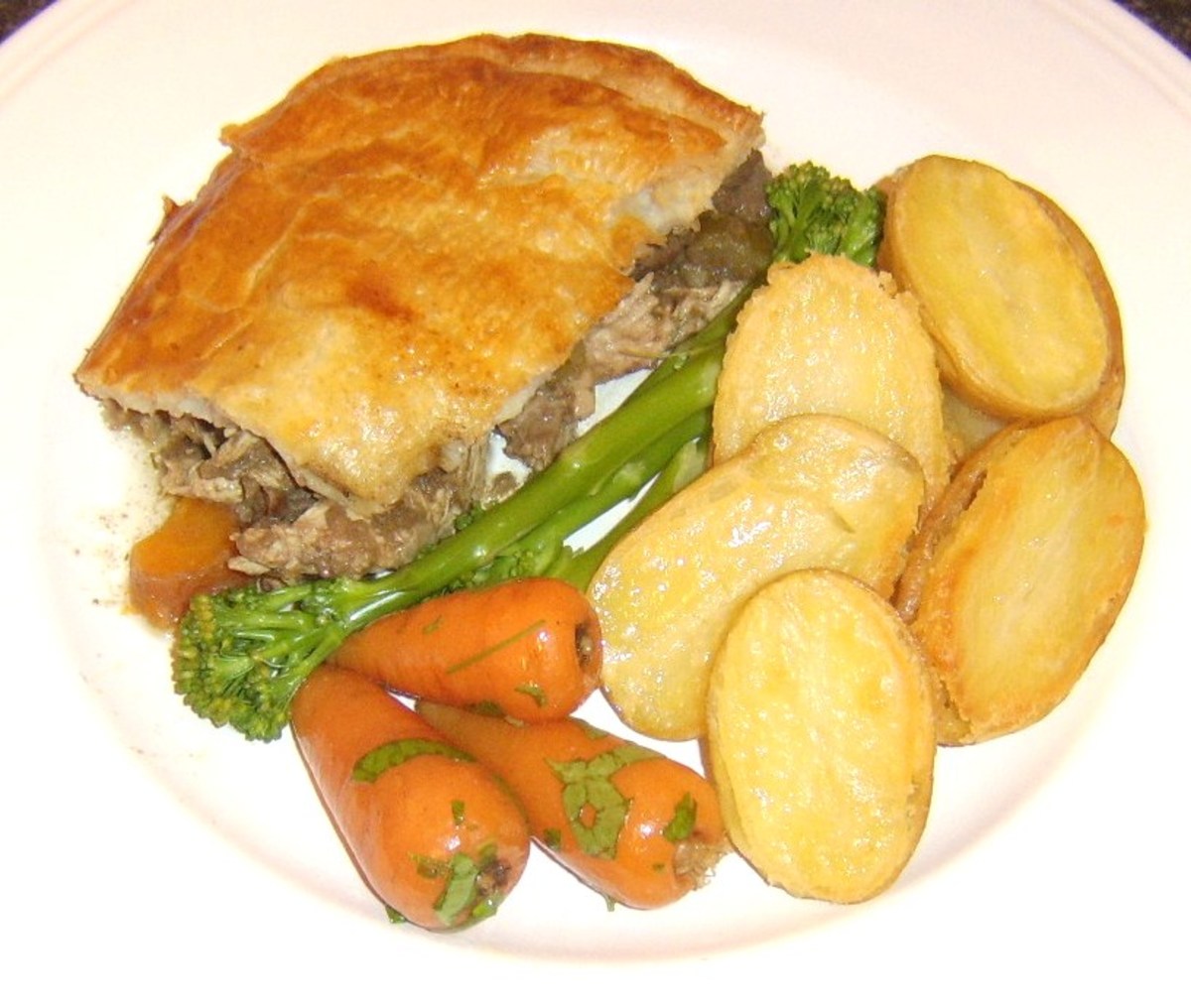 Venison and guinea fowl pie is served with pan roasted potatoes, carrots and tenderstem broccoli