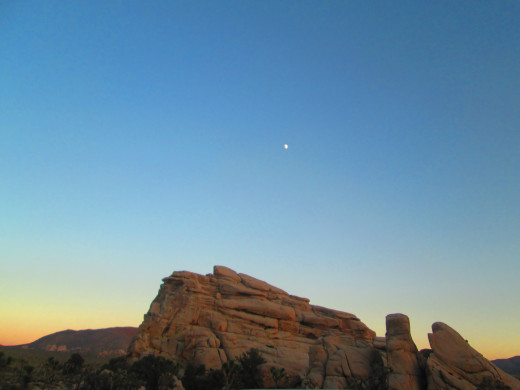 The moon above boulders at Joshua Tree National Park.