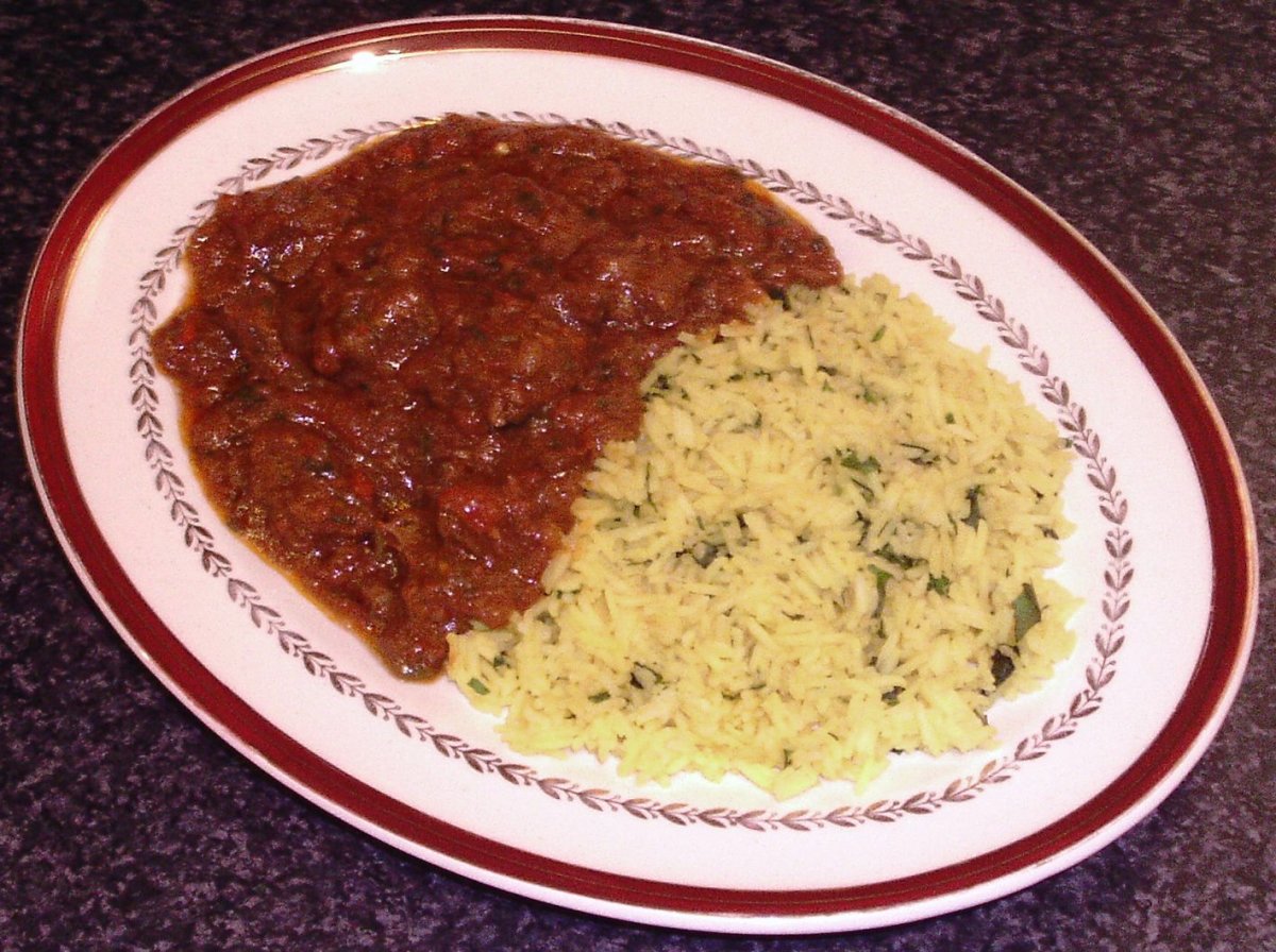 Kangaroo curry is spooned on to plate with turmeric and garlic rice
