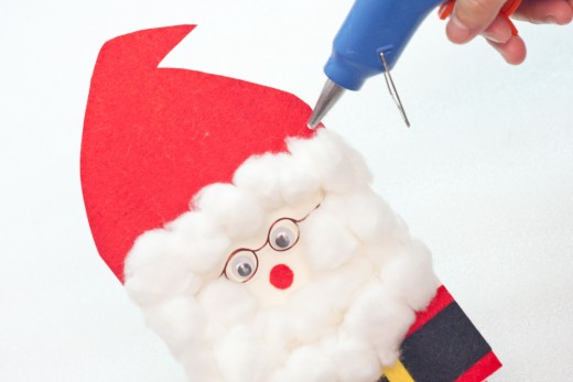 Step 18.  Place more cotton balls on the space in between the cap and the face to frame his face, this is Santa's hair. 