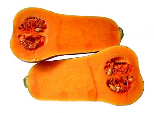 This image shows a butternut squash cut in half longways, revealing the orange color of the inside and the seeds.