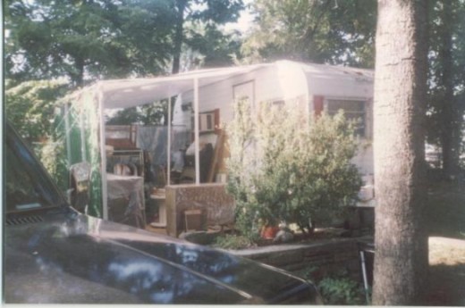 My camper with my yard sale stuff under the awning.  It had been raining so everything is draped with plastic.