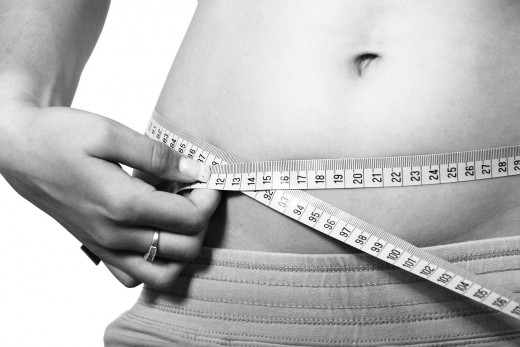 A woman measuring her waistline.
