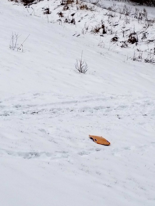 Yellow sled on freshly fallen snow in April