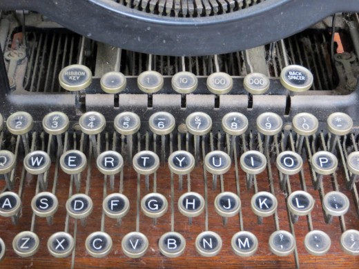Grey and black keys of a typewriter above a wooden desk.