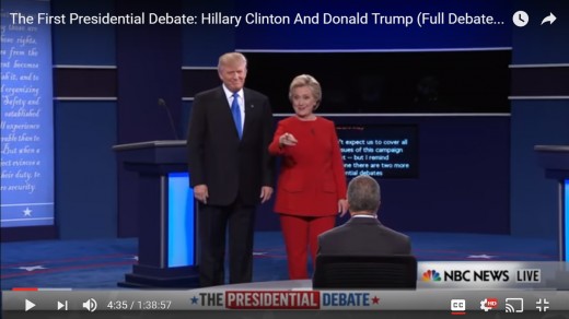 HRC points to someone in audience.  DJT stands still with arms by side.