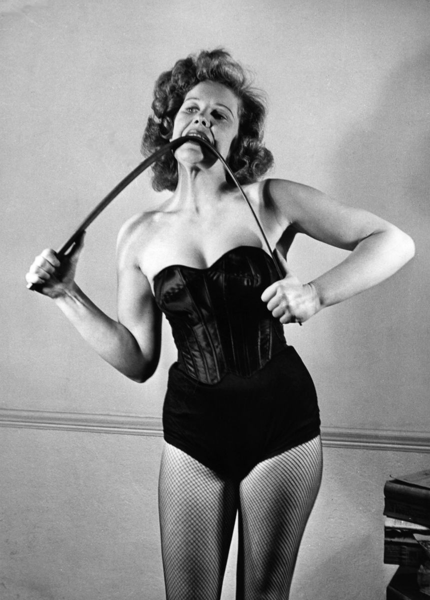 Strongwoman Joan Rhodes bends an iron bar between her teeth