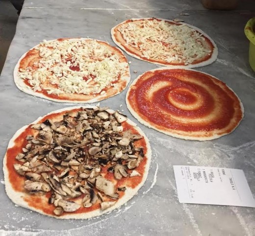 Thin crust Fungi pizza lower left before going into the oven at a pizzeria in Rome