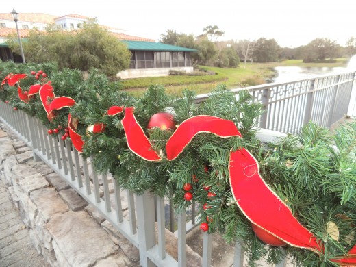 This beautifully decorated bridge railing with garlands, oversized ornaments, and a red with gold ribbon was created by the Disney decorators. Wouldn't this look great on your fence or porch railing!
